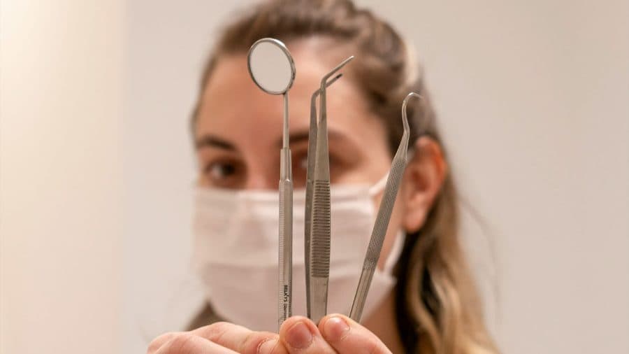 Odontóloga sosteniendo el instrumental de una limpieza dental.